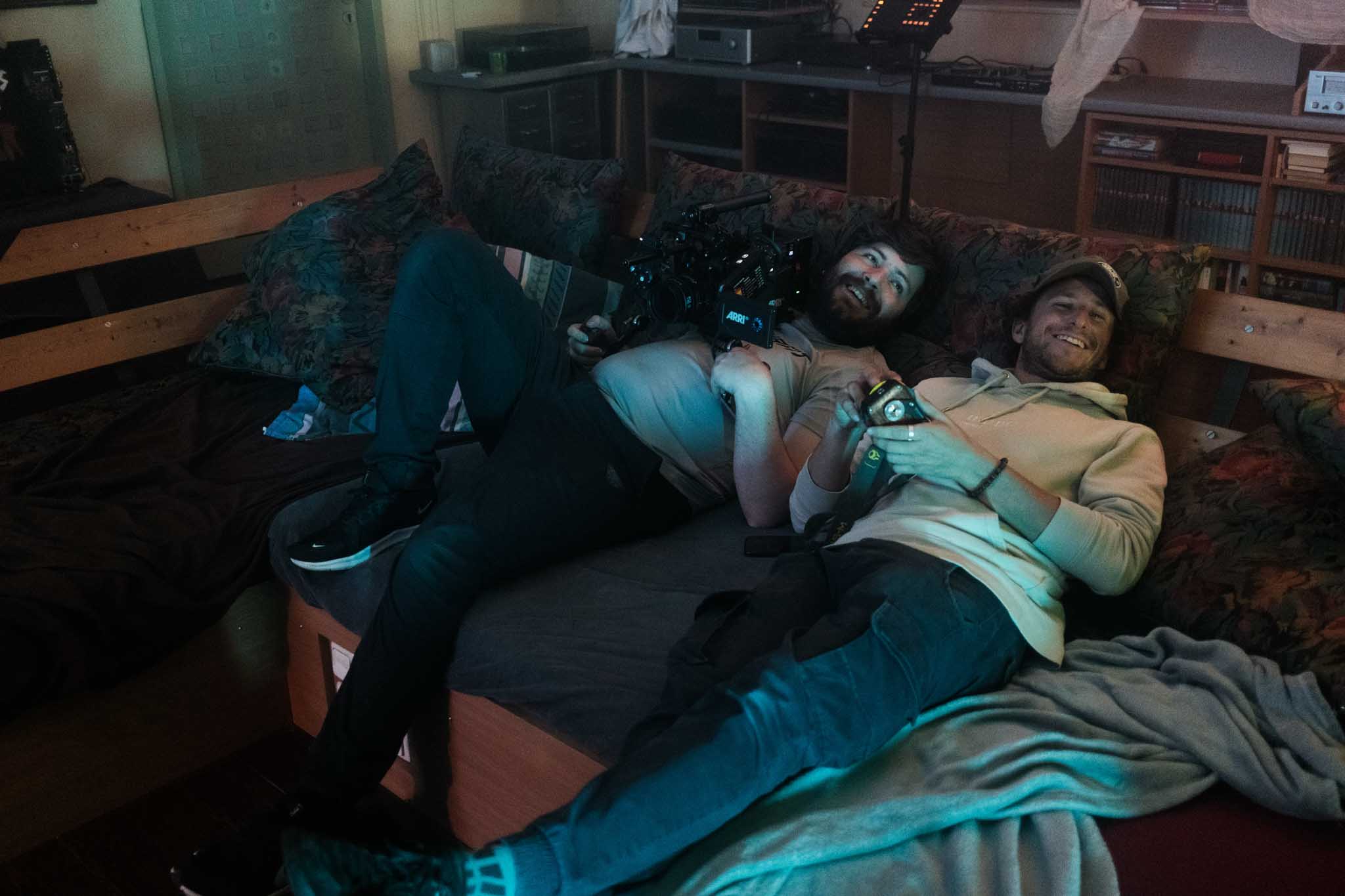 Front-facing Porsche GT3 with headlights on, carving through a chicane at twilight in alpine scenery.