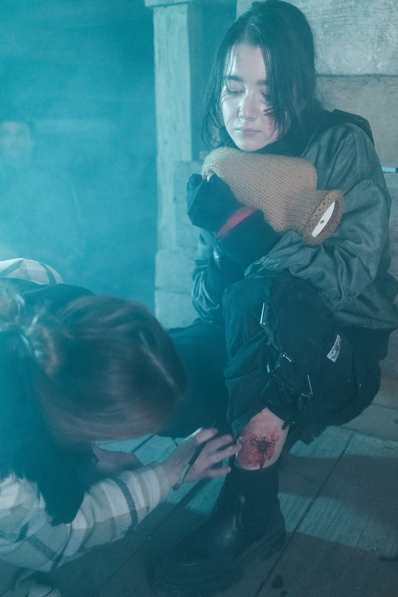Silhouette of a helmeted racing driver at dusk, mountain skyline faintly visible under violet sky.