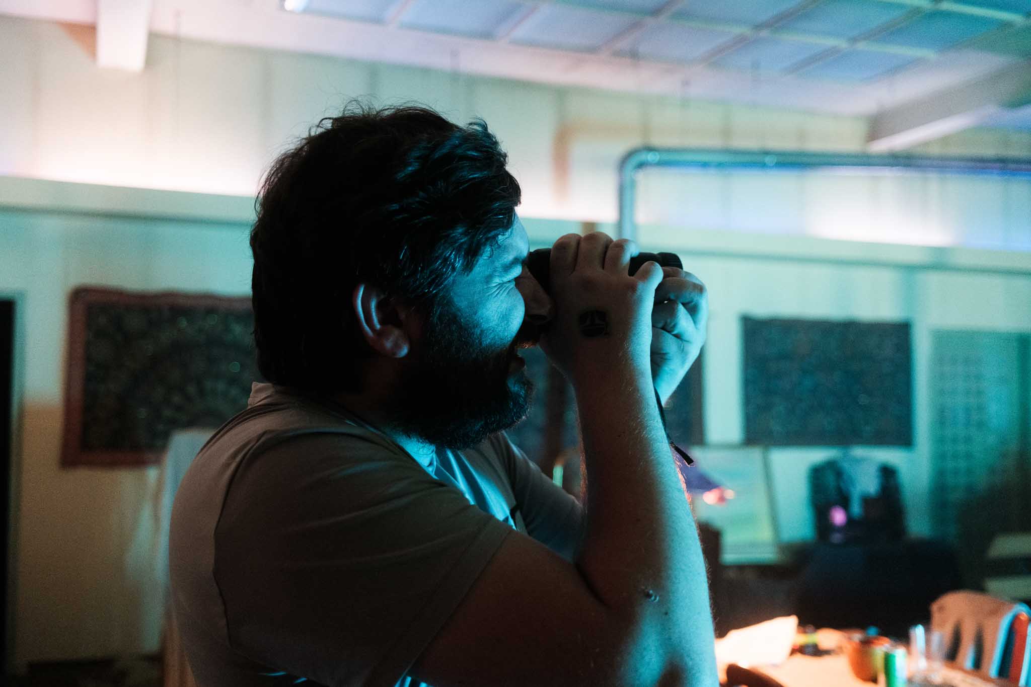 Front-facing Porsche GT3 with headlights on, carving through a chicane at twilight in alpine scenery.
