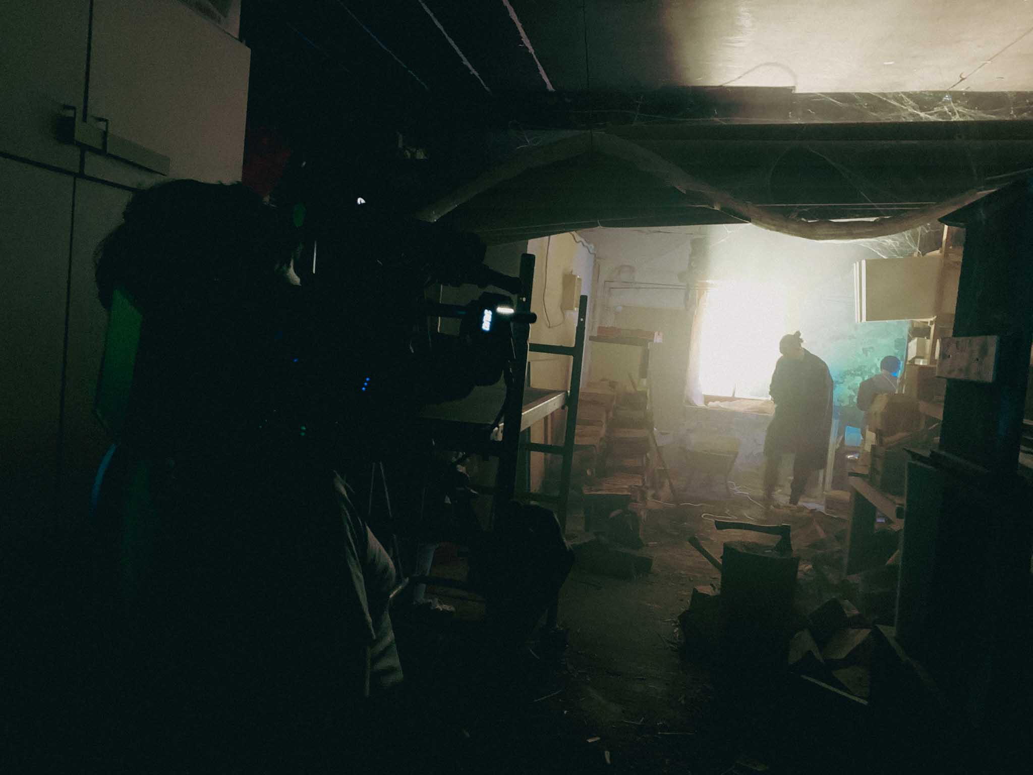 Front-facing Porsche GT3 with headlights on, carving through a chicane at twilight in alpine scenery.