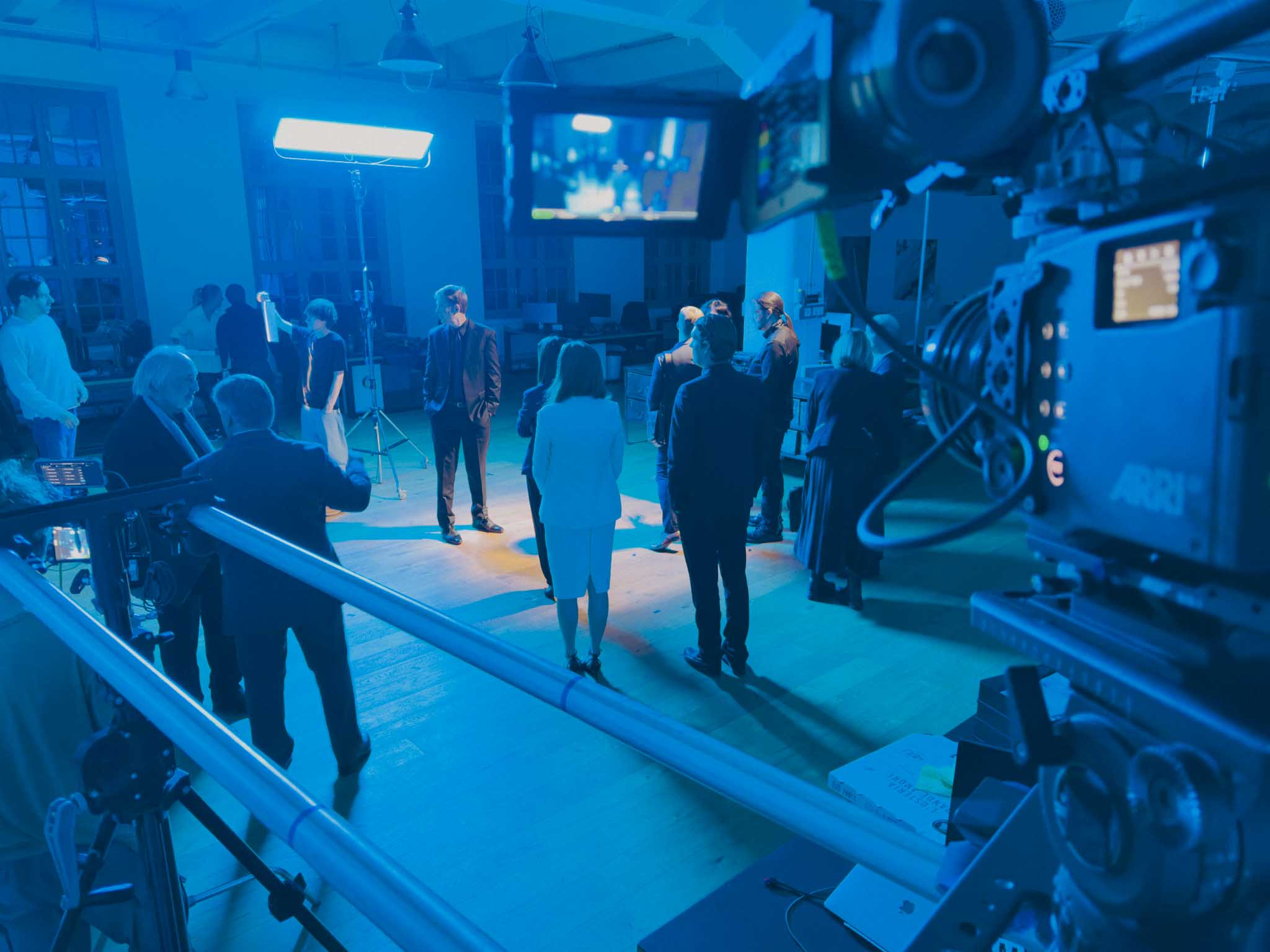 Aerial view of an alpine lakeside road with avalanche gallery; tiny sports car speeds along the shoreline.