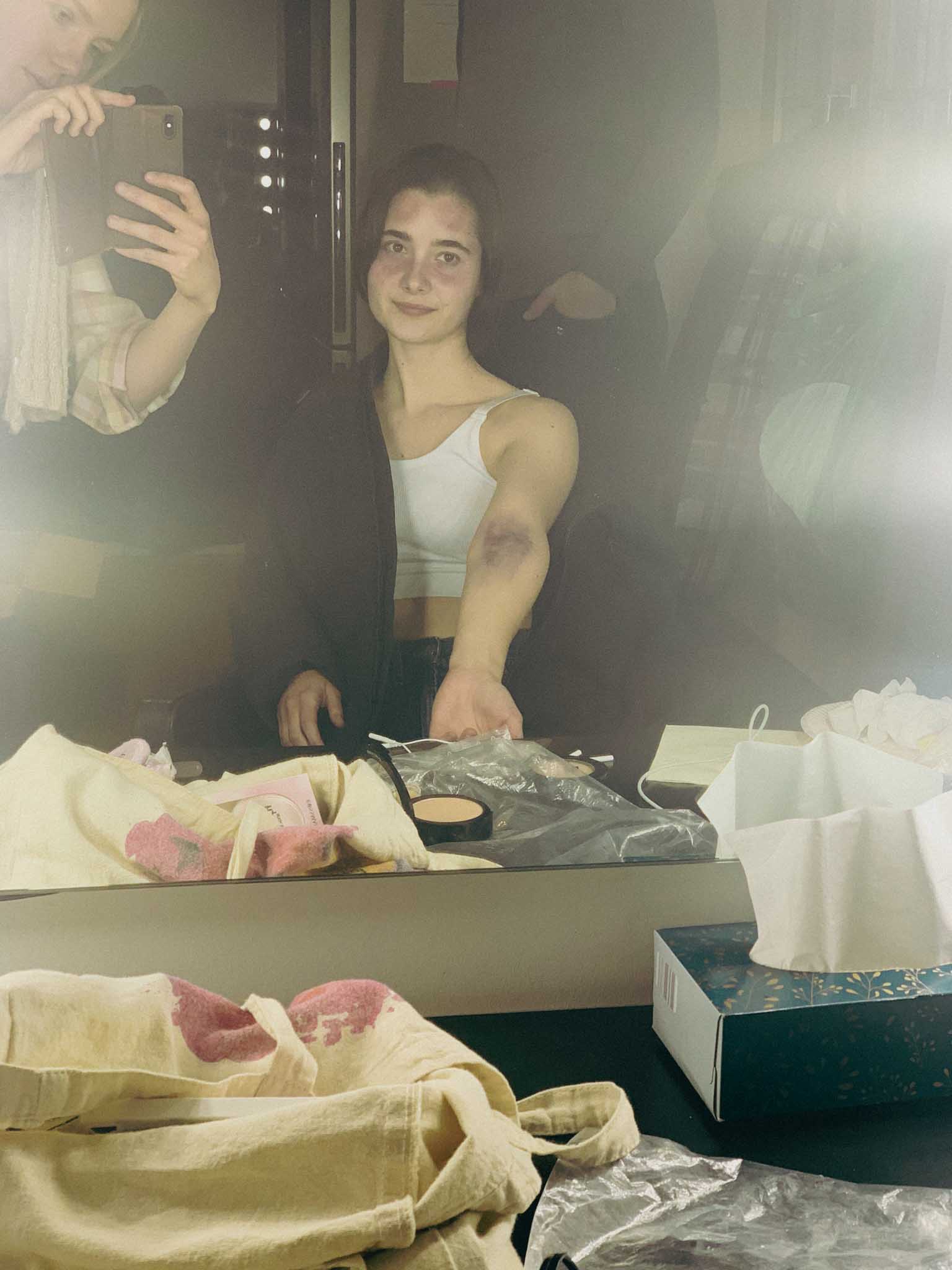 Front-facing Porsche GT3 with headlights on, carving through a chicane at twilight in alpine scenery.