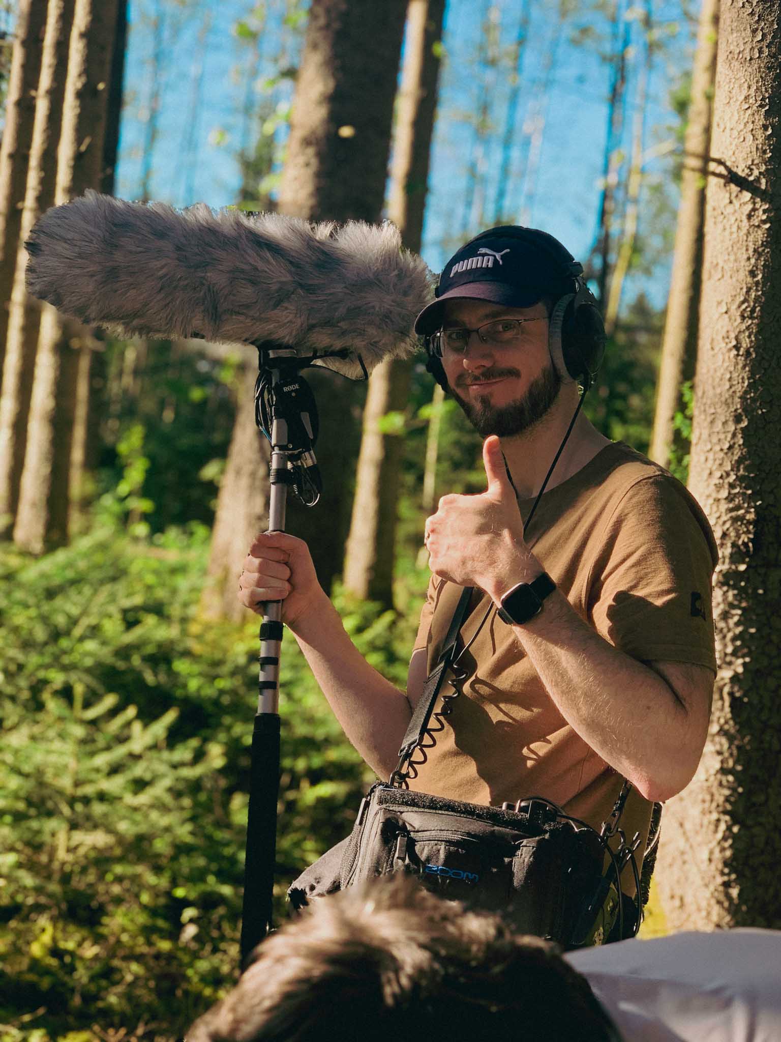 Aerial view of an alpine lakeside road with avalanche gallery; tiny sports car speeds along the shoreline.
