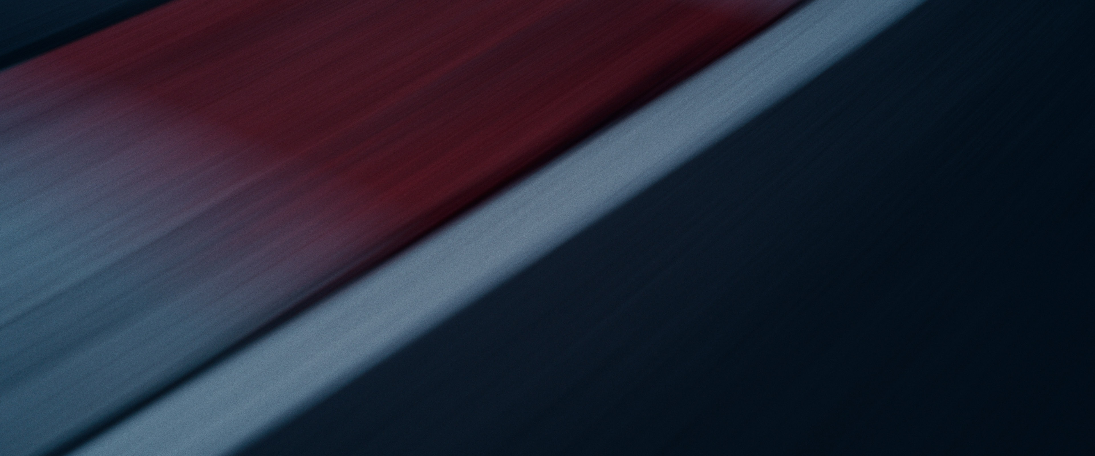Abstract motion-blur of red and white kerb stripes on dark asphalt, evoking racetrack speed.